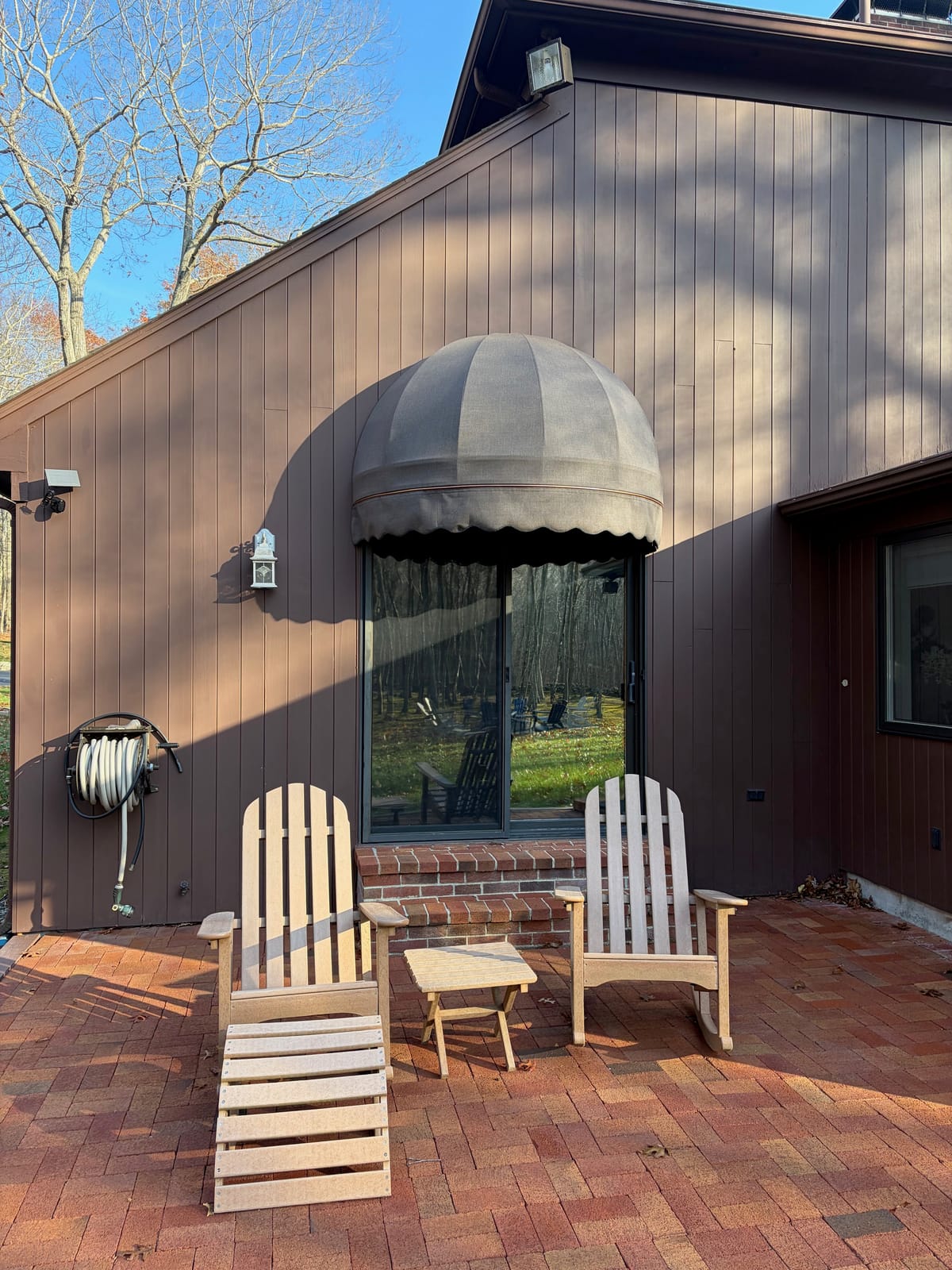 Dome awning over a sliding glass door beside a brick patio