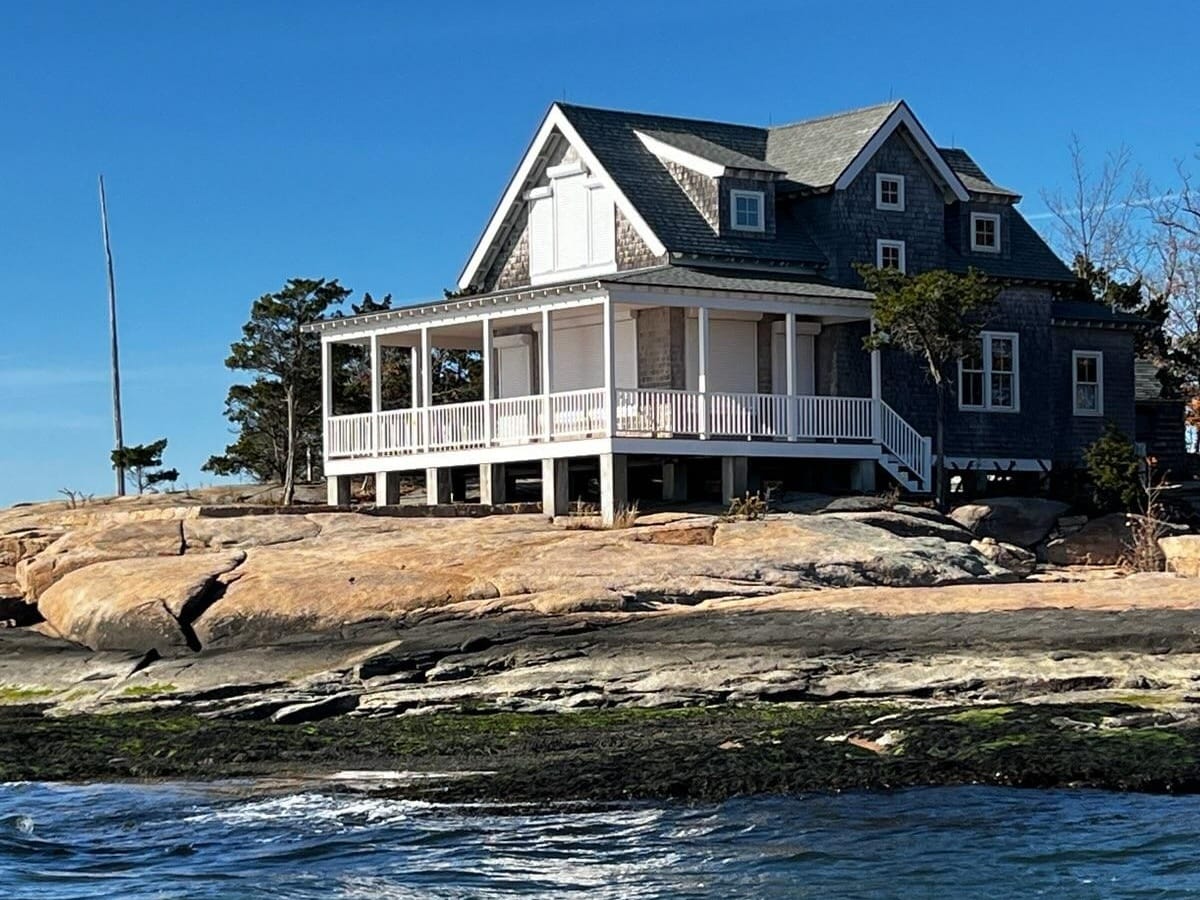 Thimble Islands cottage with roll-down hurricane shutters closed, seen from the water