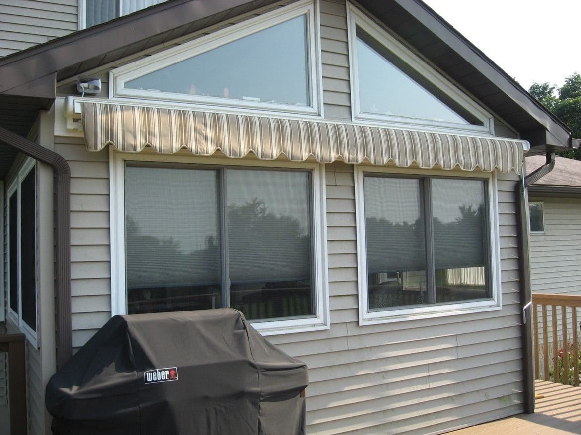 Perfecta retractable awning in Toga stripe, closed above a wall of sunroom windows