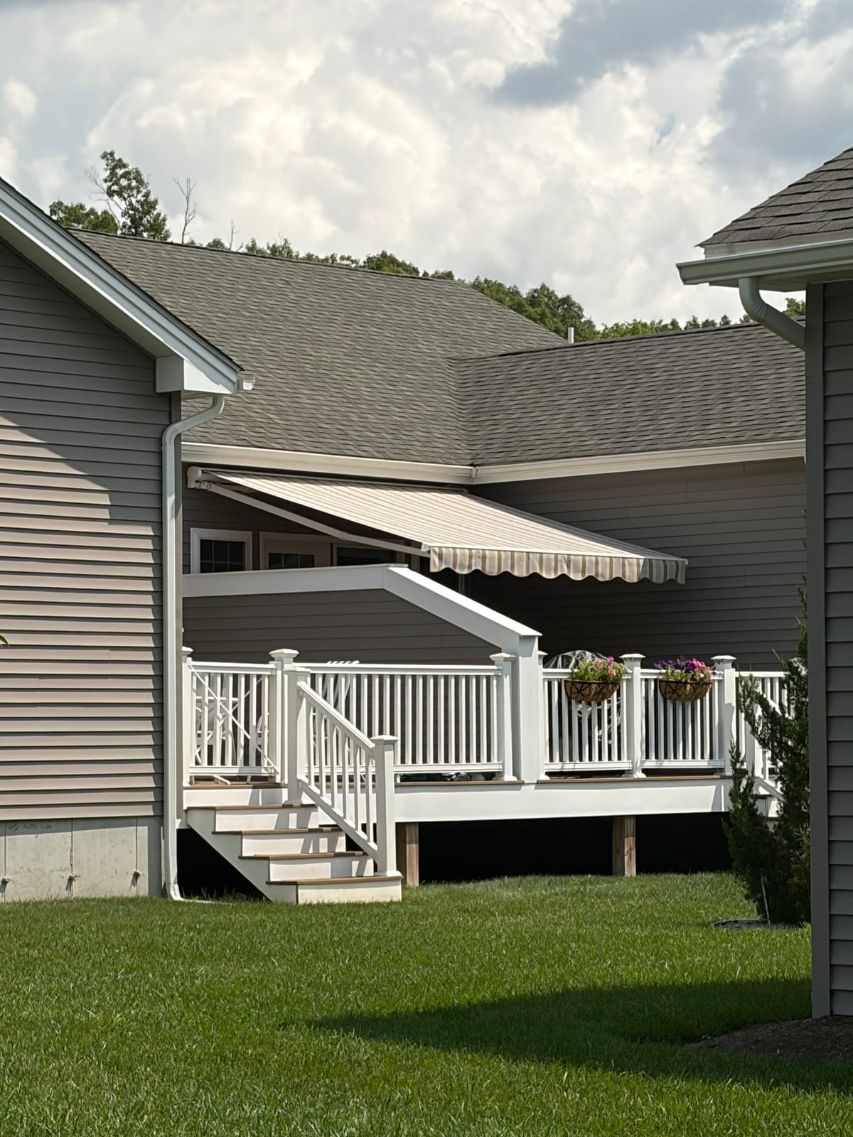 Tan striped retractable awning shading a raised deck with white railings