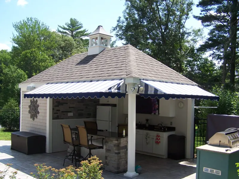Navy striped awnings on three sides of a backyard pool-house bar