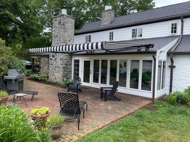 Black and white striped retractable awning on a stone patio