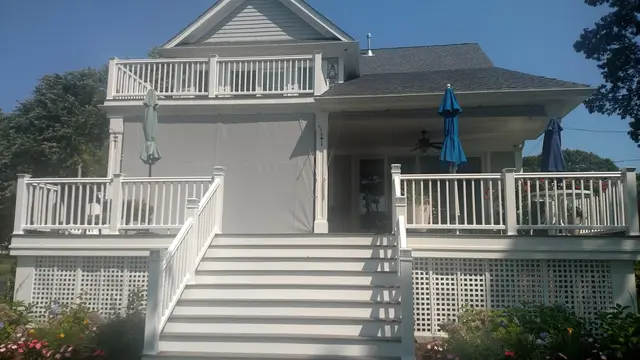 Roll-up solar shade curtain lowered across the porch of a coastal home