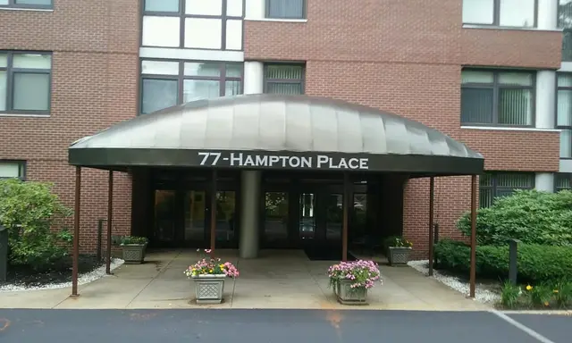 Bronze dome entrance canopy with building lettering at the 77 Hampton Place apartments