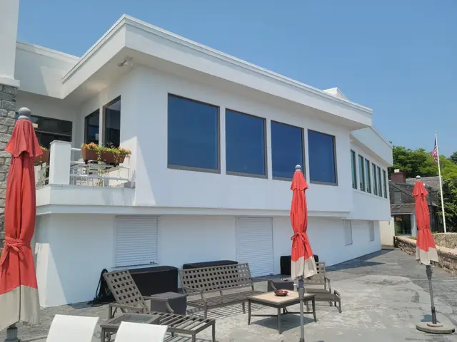 Hurricane shutters closed over the lower-level openings behind the patio seating