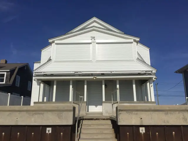 Oceanfront beach house with white roll-down hurricane shutters closed over every window and the porch