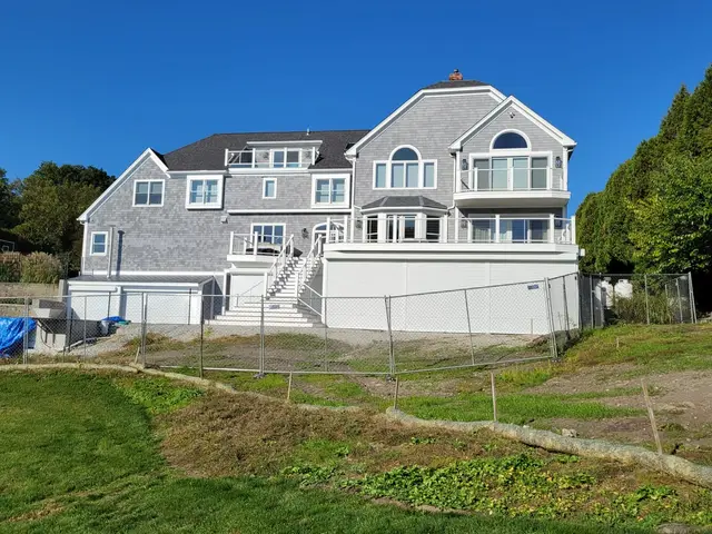 White hurricane shutters closed across the under-deck level of a shingle estate