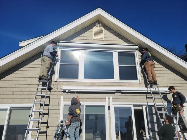 Crew installing hurricane shutter housings on a beach cottage gable