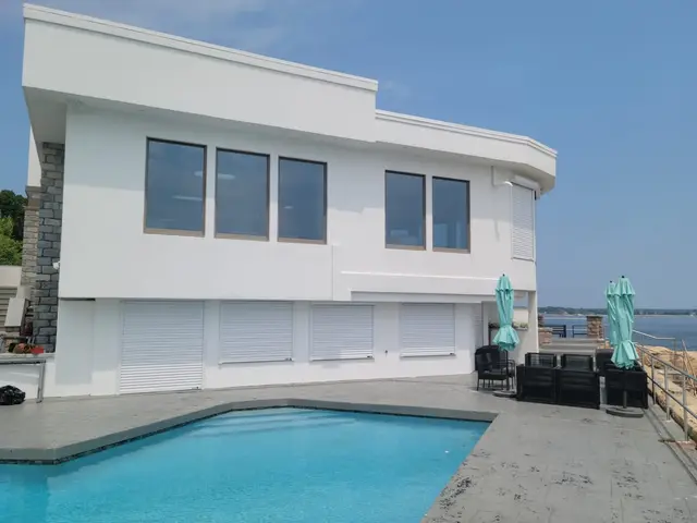 White roll-down hurricane shutters closed across the pool level of a waterfront home