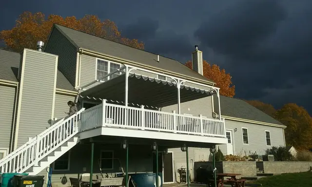 White canopy pergola over a raised deck under a storm sky