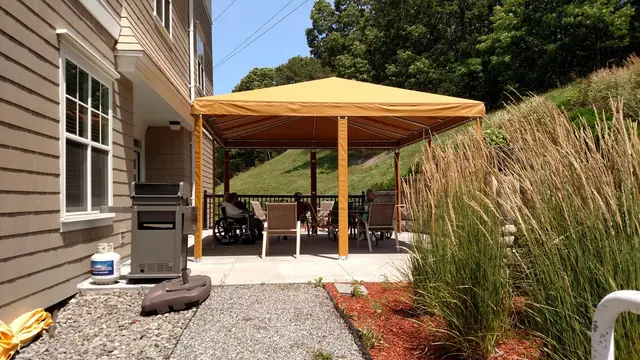 Gold freestanding hip canopy with wrapped posts over a shaded sitting patio
