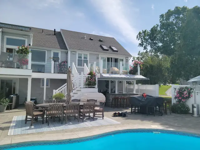 Backyard pool patio with a striped awning over the under-deck bar