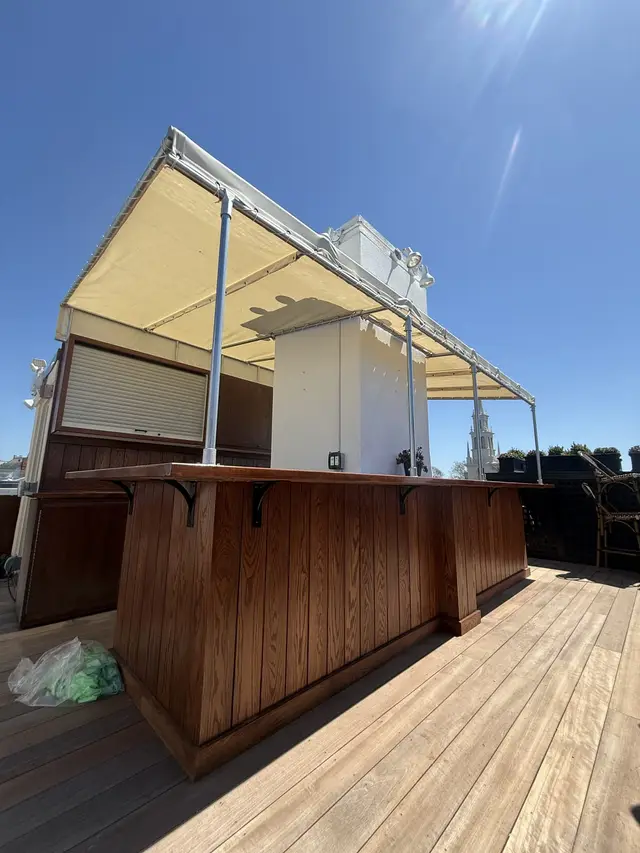 Canvas canopy over a rooftop bar with roll-up service shutters