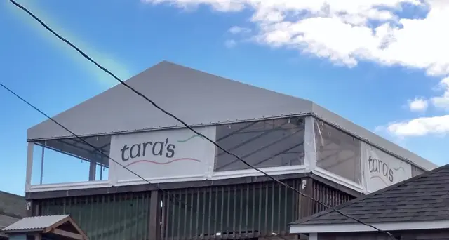 White hip canopy with clear roll-down curtains over the upper deck at Tara's