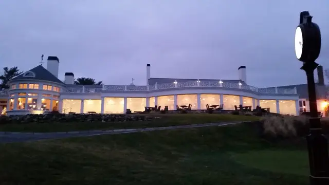 Clear vinyl winter enclosure wrapping a club veranda at dusk