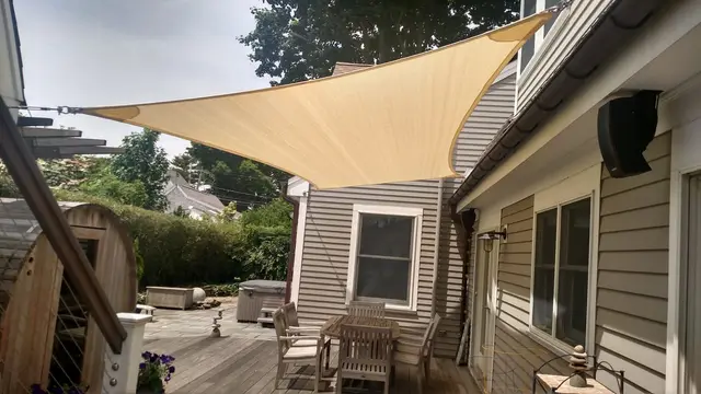 Sand-colored shade sail over a backyard deck dining area in Jamestown, RI