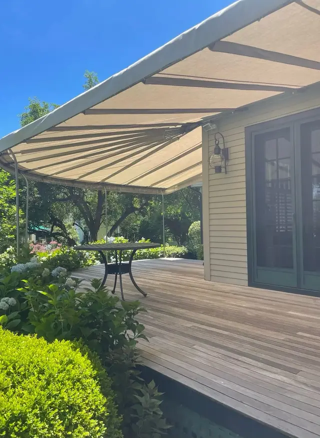 Curved-frame canopy over an ipe deck, hydrangeas in bloom
