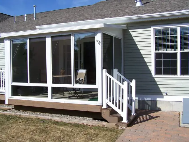 Sage-green sunroom addition with stone planter landscaping