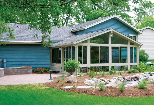 White gable sunroom on a blue home with fresh landscaping