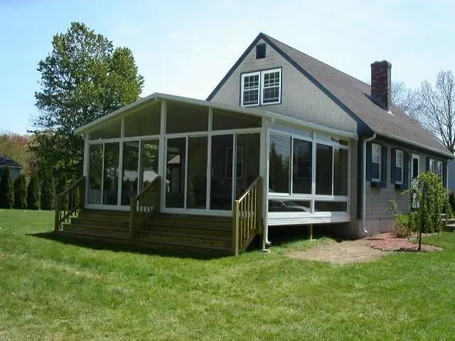 Full-width sunroom addition on a gray cape in Swansea, MA