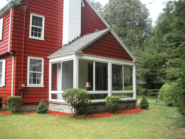 White gable sunroom against a deep-red home