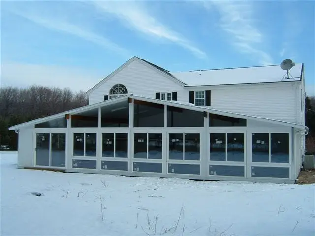 Full-length glass room across the back of a farmhouse, mid-winter