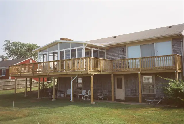 Patio room under a raised deck, cedar-shingled home
