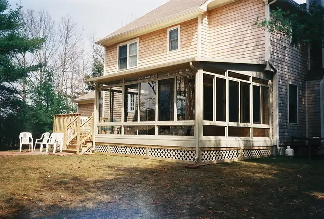 Sunroom tucked under the deck of a cedar-shingled home