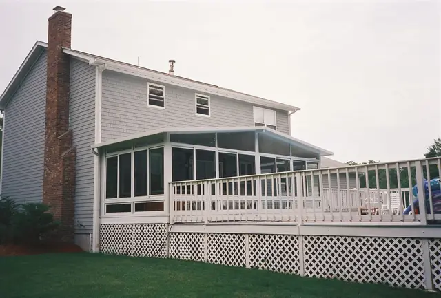 Full-width sunroom with lattice skirt on a gray home