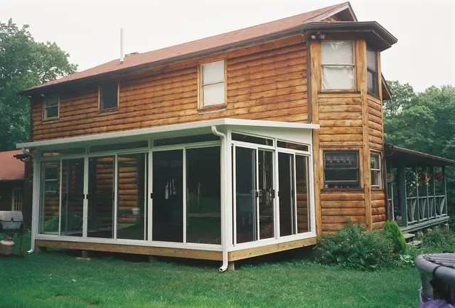 White sunroom addition on a log-sided house