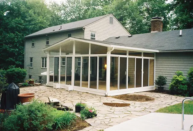 Sunroom addition with sliding door on a gray colonial