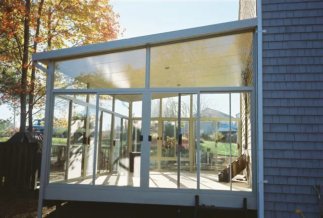 Glass sunroom beside a stone chimney