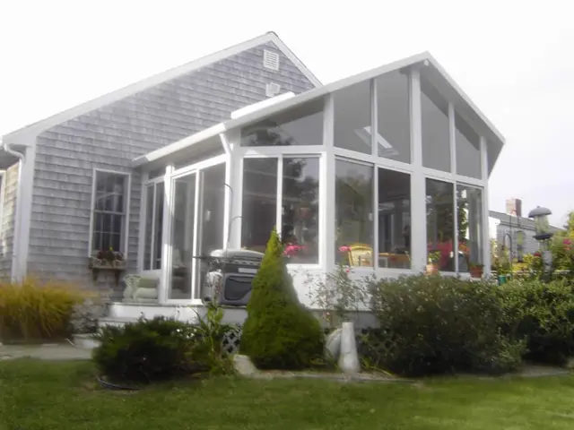 White gable sunroom with flower box on a gray-shingled home