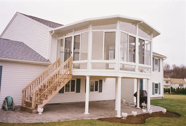 Two-story curved sunroom addition with deck stairs
