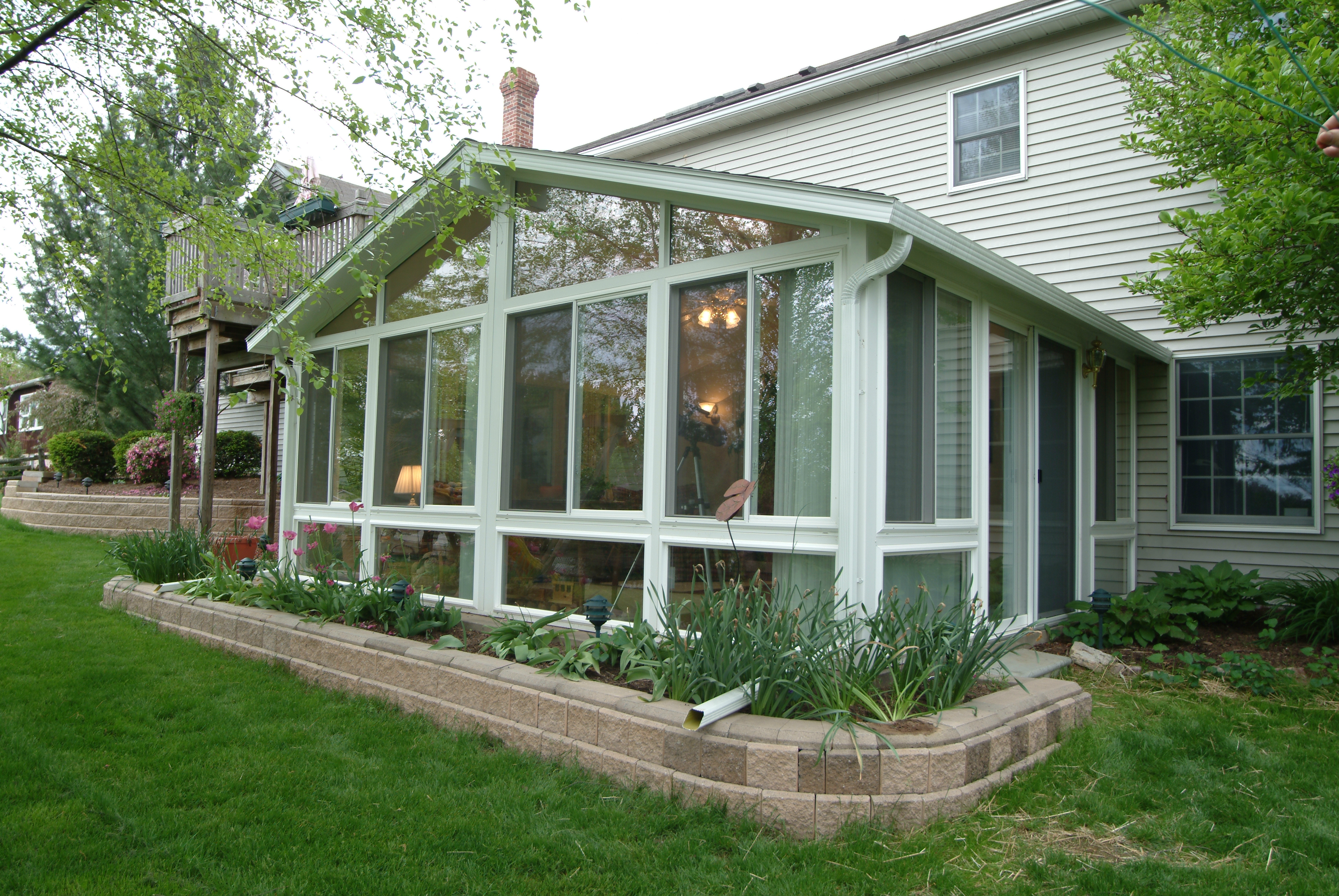 Gable sunroom with warm interior lighting and landscaped yard